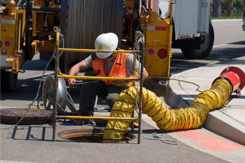 Construction worker who works in utility and maintenance beside a maintenance hole